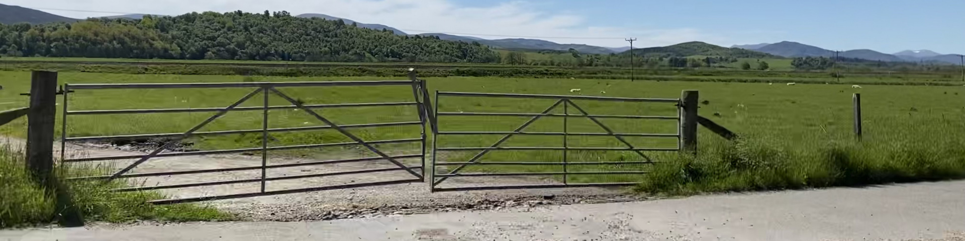 A metal farm gate near Kincraig with hills beyond.