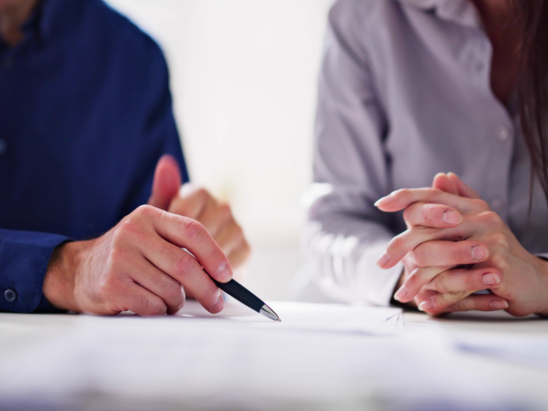 Close up of 2 people signing an agreement during a mediation session.