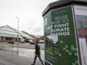 Reuse Land to Help Fight Climate Change poster in place with a passer-by