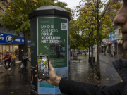 A passer-by looking at a MyLand poster on their phone